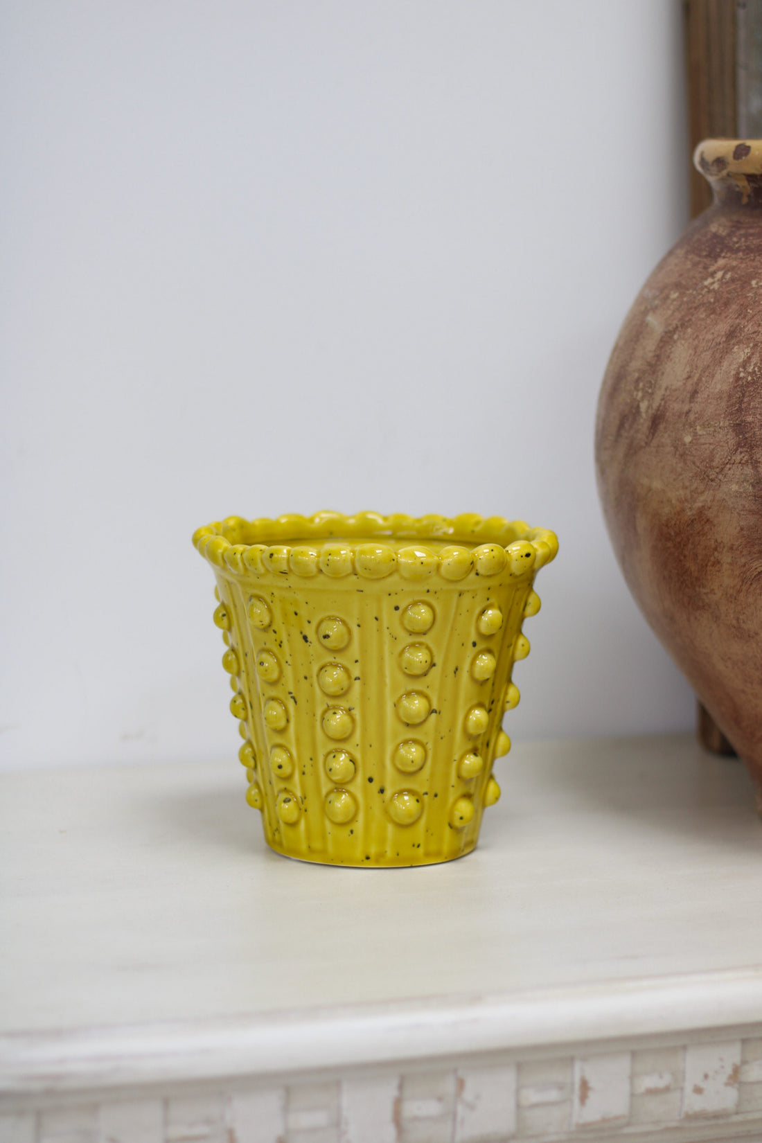 Yellow textured pot on a white surface with a neutral background