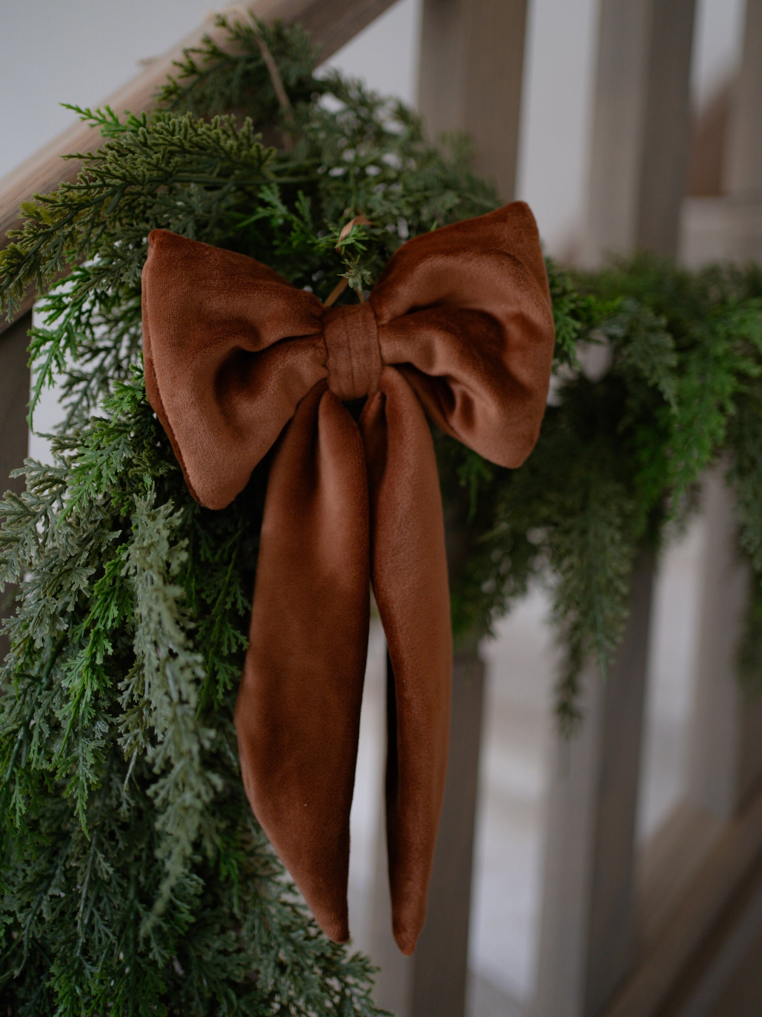 Green wreath with a caramel velvet bow on a white railing
