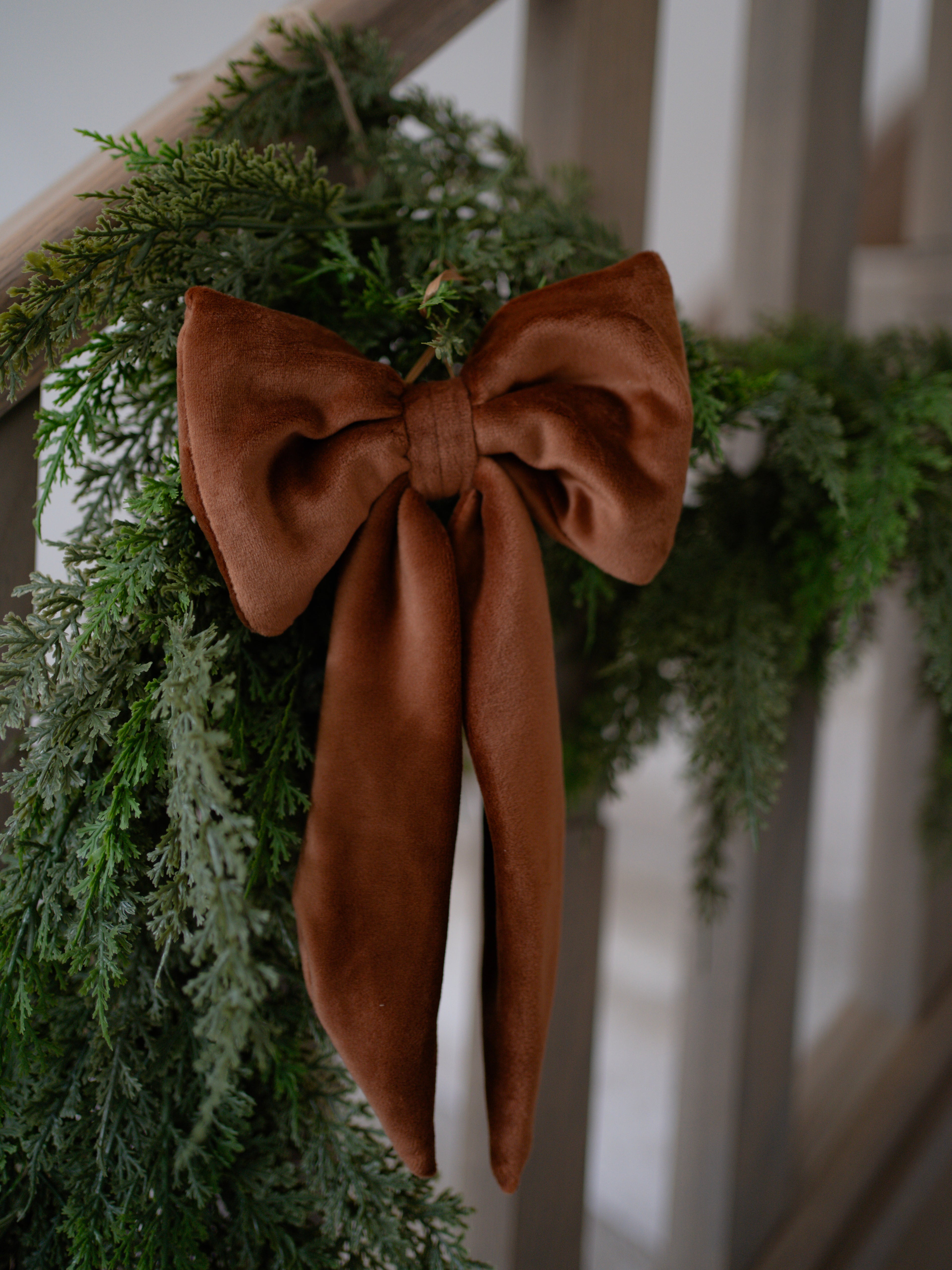 Green wreath with a caramel velvet bow on a white railing