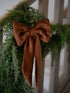 Green wreath with a caramel velvet bow on a white railing