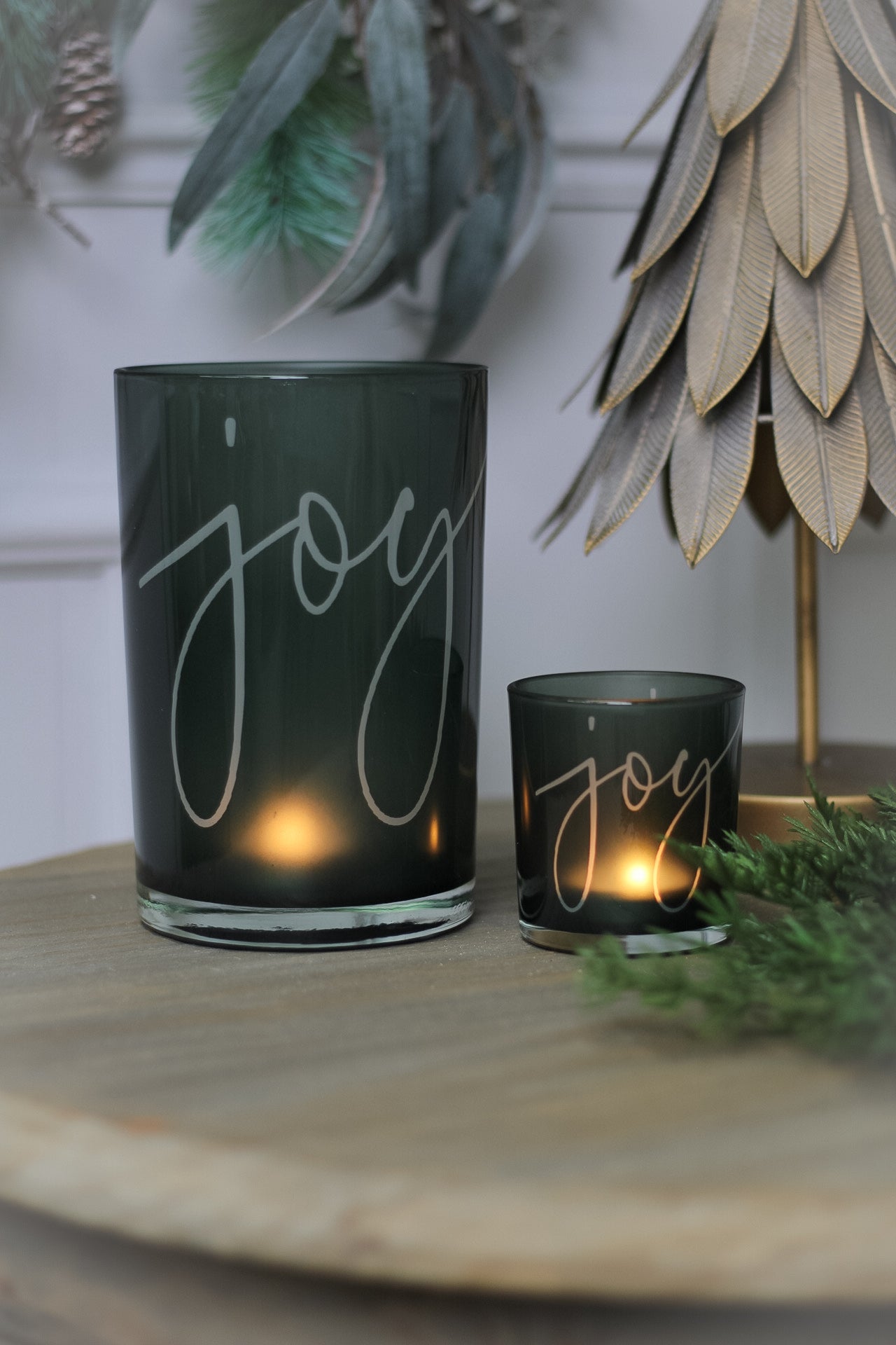 Two green glass tea light holders with the word &