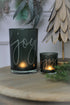 Two green glass tea light holders with the word &