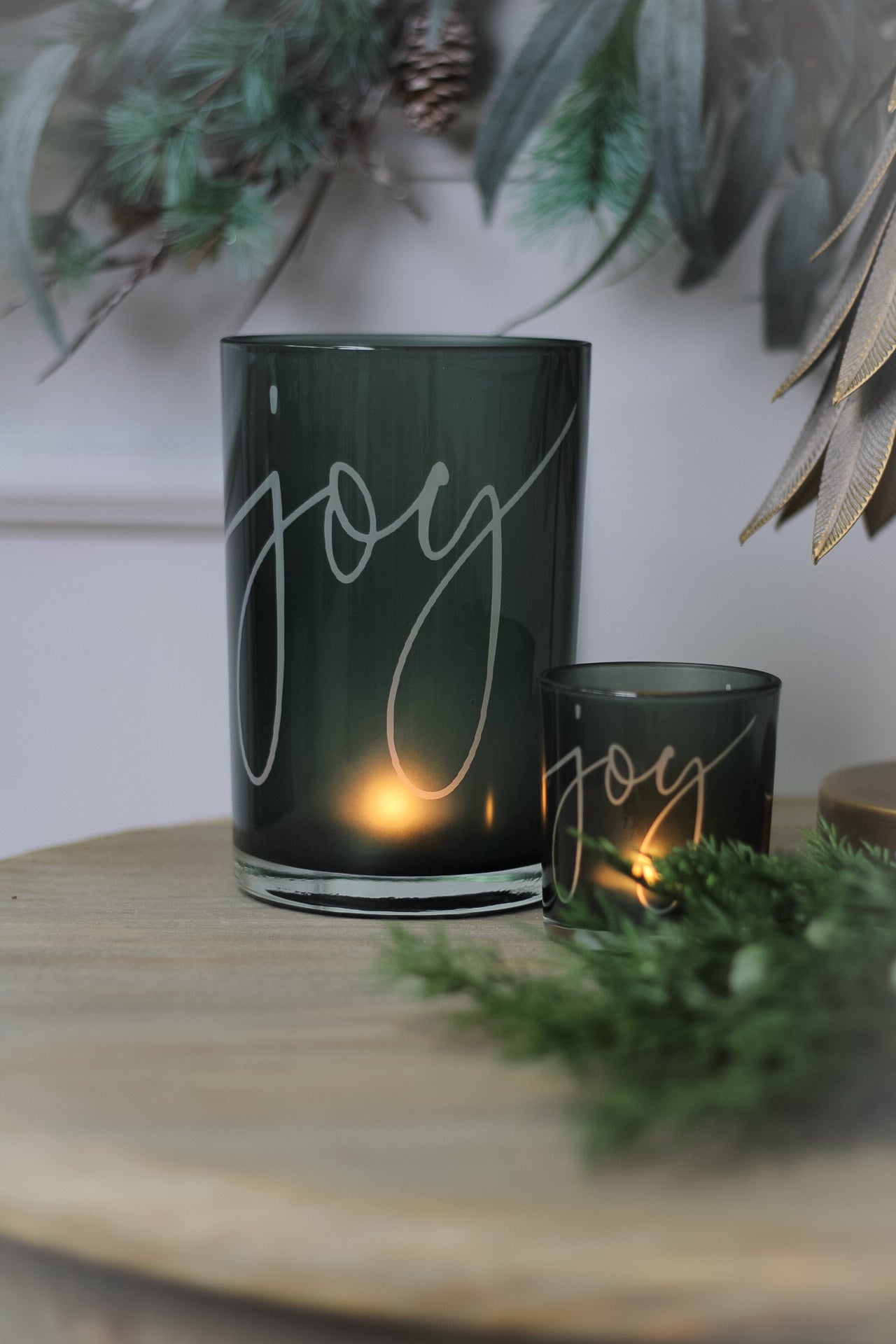 Two green glass tea light holders with the word &