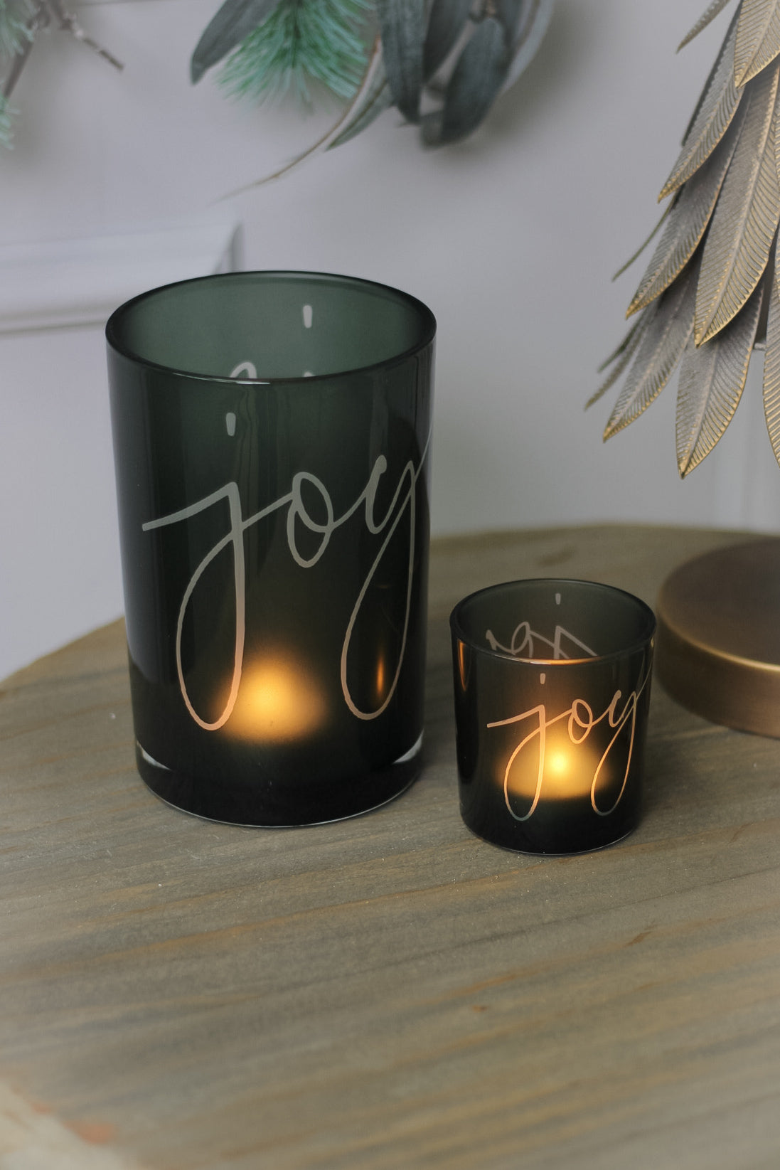 Two green glass tea light holders with the word &
