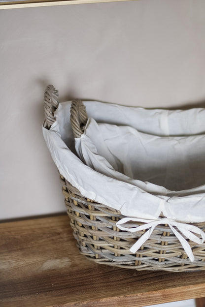 Wicker basket with white fabric lining on a wooden surface