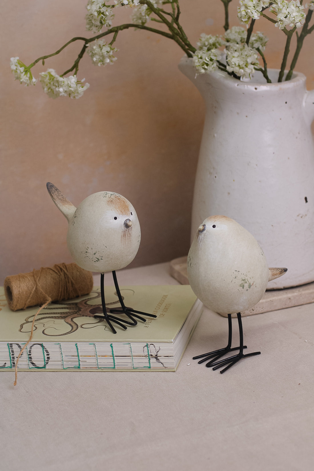 A set of two decorative stone-textured birds with long black legs, placed on a kitchen countertop.