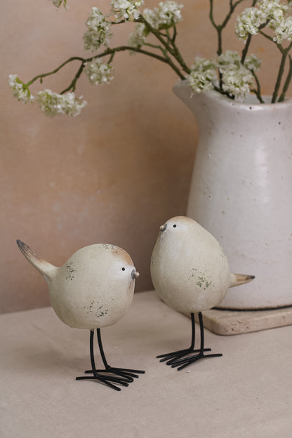 A set of two decorative stone-textured birds with long black legs, placed on a kitchen countertop.