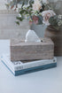 woven rattan rectangular tissue box cover on top of coffee table books.
