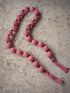 A festive christmas garland made of red and white striped fabric beads, laid out on a textured beige stone surface.