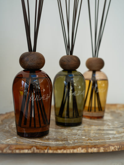 Three diffuser bottles with wooden caps on a wooden surface