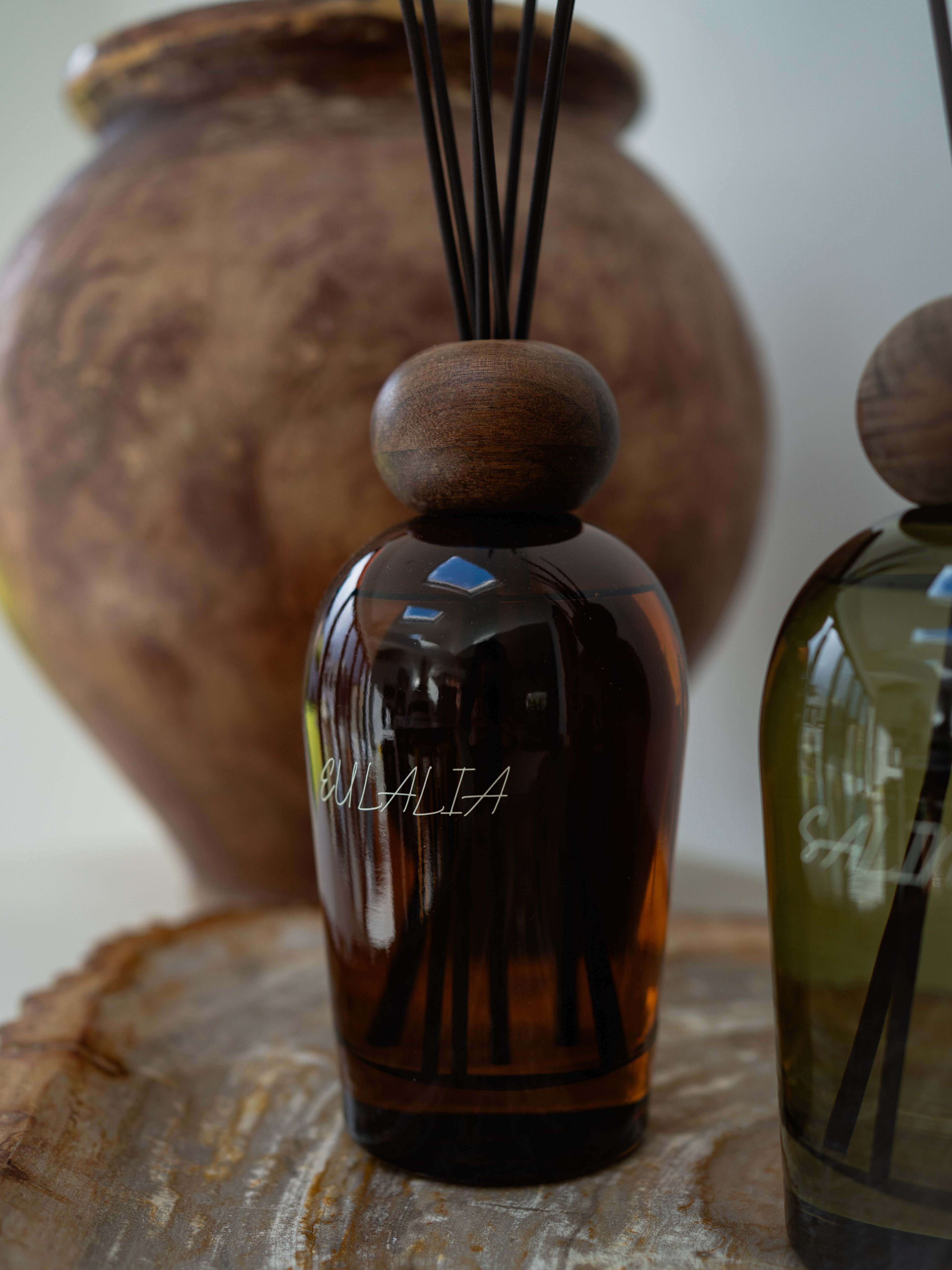Brown diffuser bottle with wooden cap on a textured surface