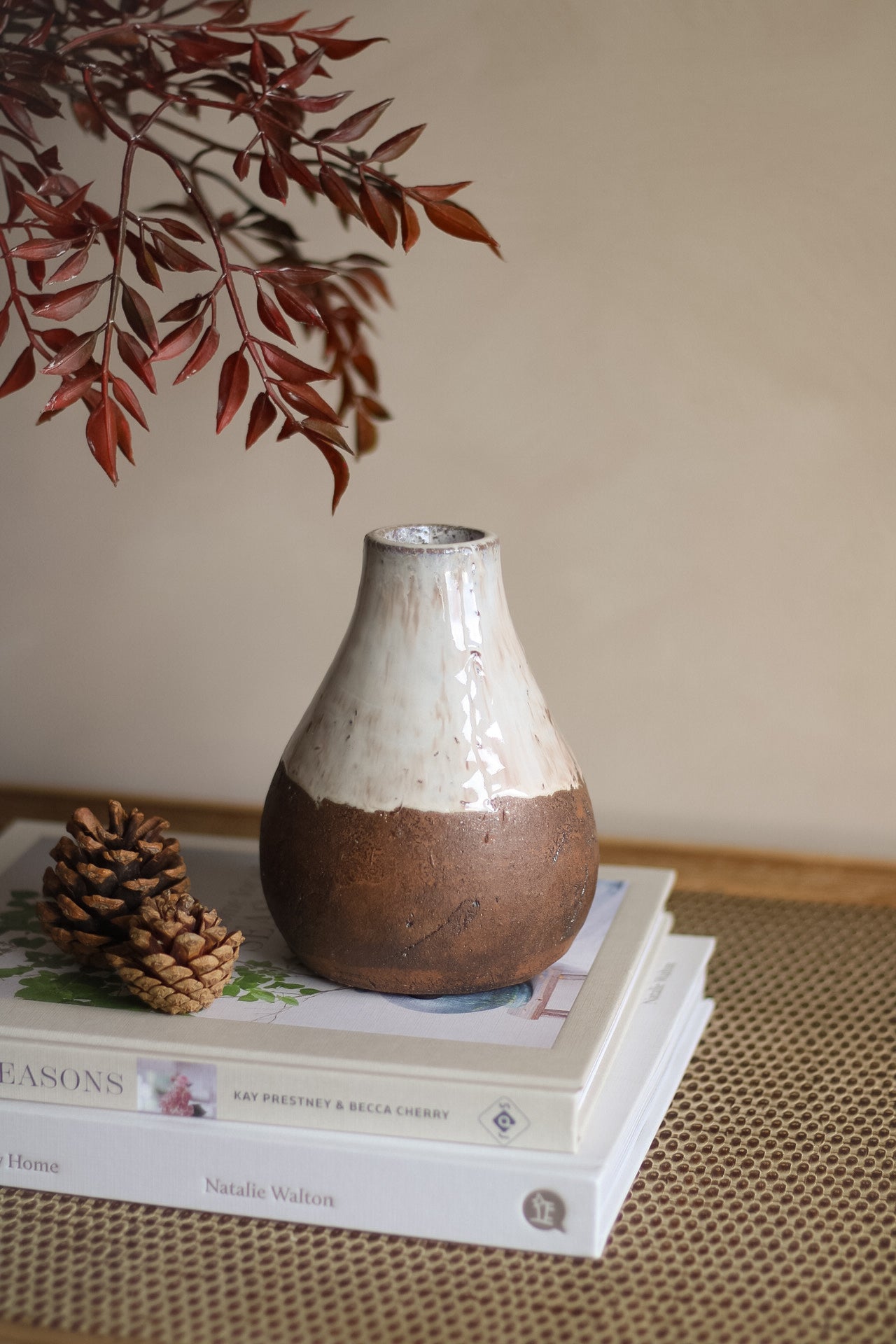 Ceramic vase on a stack of books with a blurred branch in the background