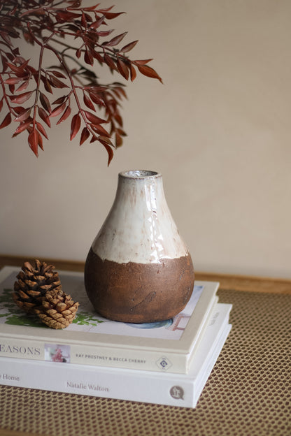 Ceramic vase on a stack of books with a blurred branch in the background
