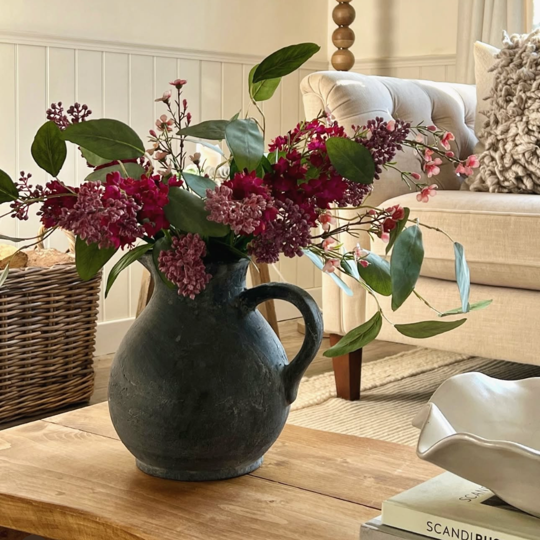 Charcoal rustic jug with faux lilac and silver dollar eucalyptus stems on coffee table in living room