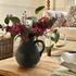 Charcoal rustic jug with faux lilac and silver dollar eucalyptus stems on coffee table in living room