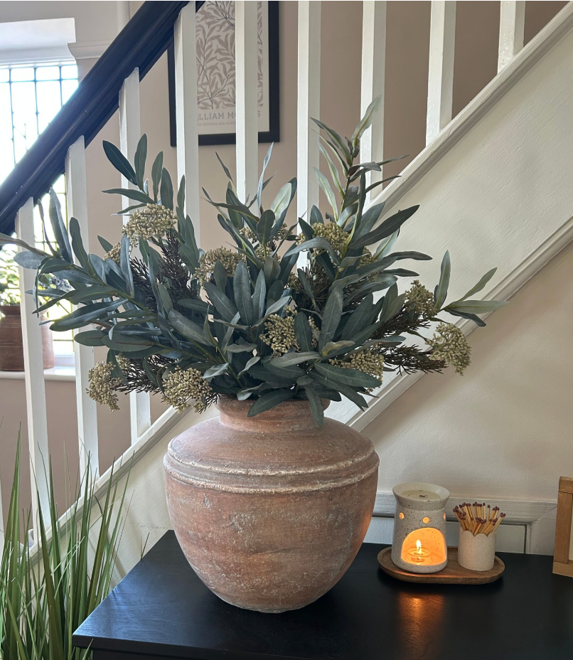 Brown rustic pot filled with faux foliage on hallway table