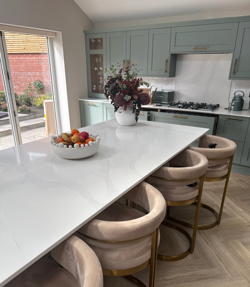 Modern kitchen with a white island, fruit bowl, and decorative vase.