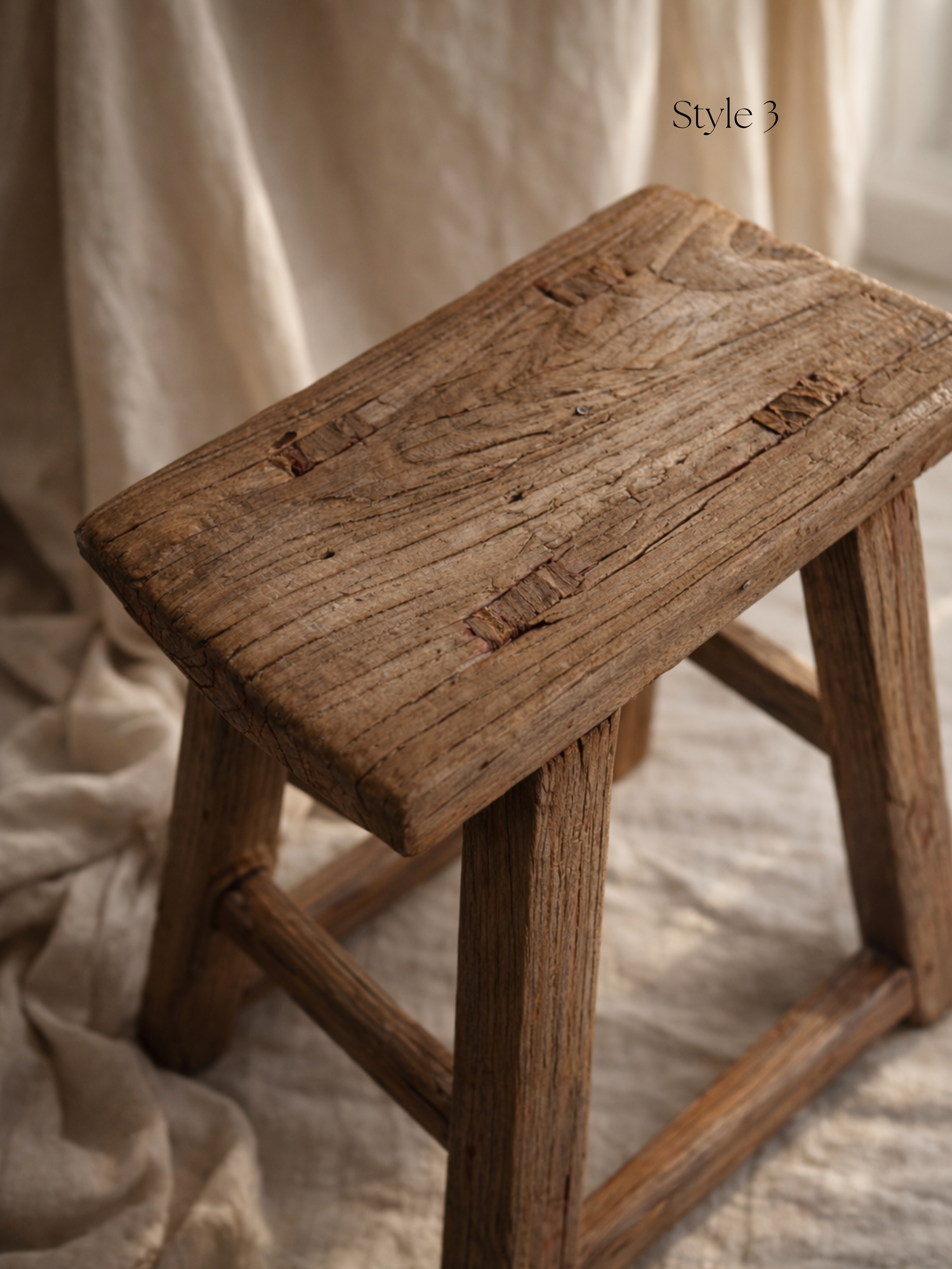 Wooden stool with a rustic finish on a soft, beige fabric background for home decor