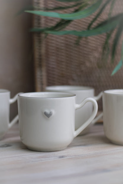 up close of white ceramic mug with embossed grey heart