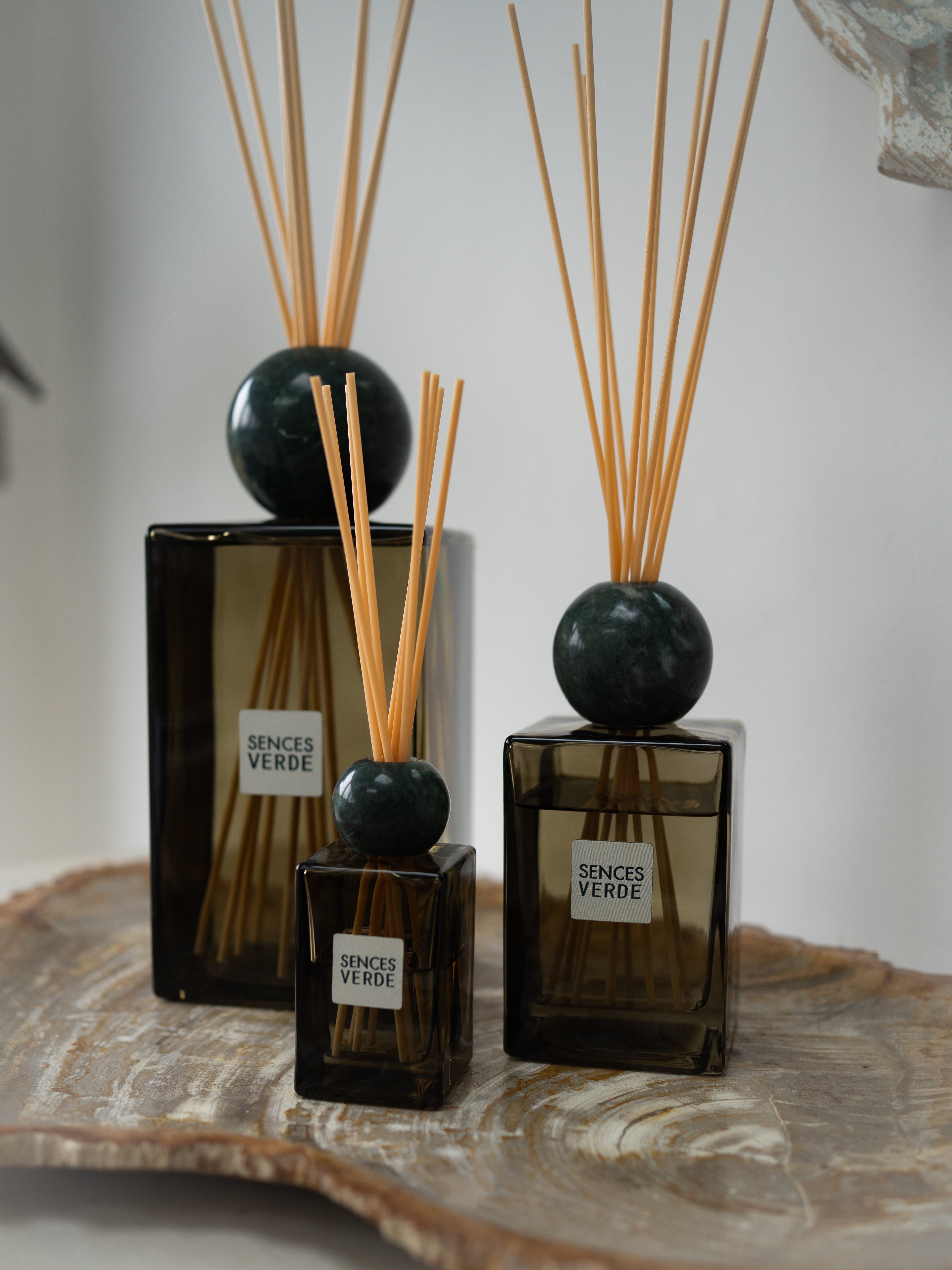 three green glass reed diffusers with dark green marble spheres and natural wood reeds, labeled &