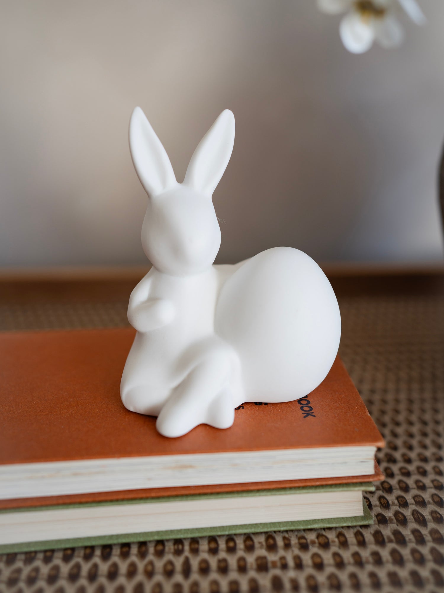 White rabbit figurine on a stack of books with a blurred background