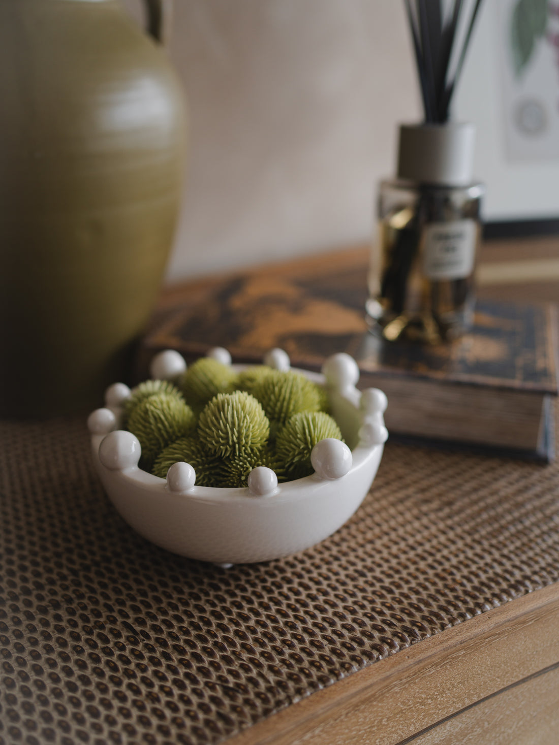 Small white bowl with green decorative echinops balls on a textured surface